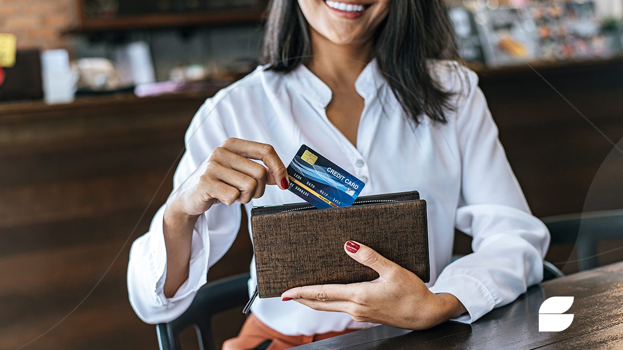 mulher guardando cartão de crédito com limite alto na bolsa