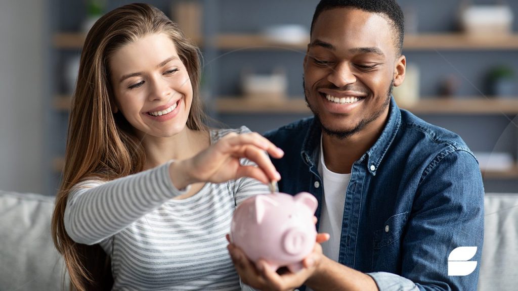 casal que sabe como guardar dinheiro colocando moeda em porquinho